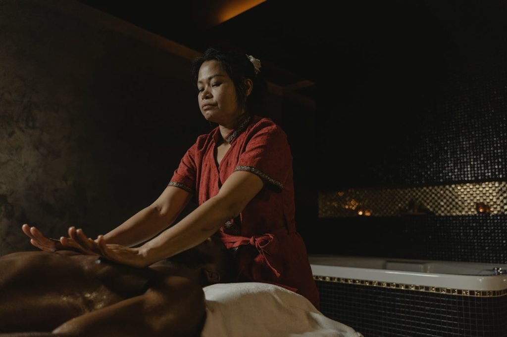 Professional masseuse performing relaxing spa massage in dimly lit room.